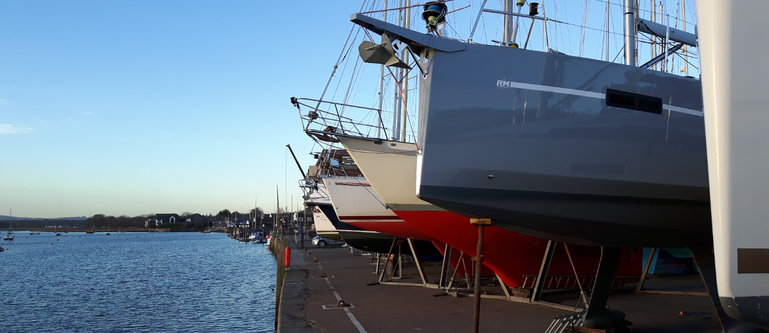 Boats parked on land, next to the sea